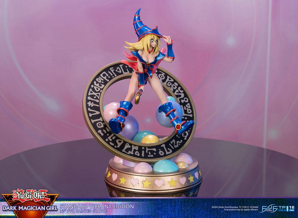 Figurine de Dark Magician Girl en PVC, posée dans un cercle magique décoré de runes, avec des sphères pastel à la base. Elle porte sa tenue bleue et rose emblématique, avec un chapeau pointu et une pose dynamique.