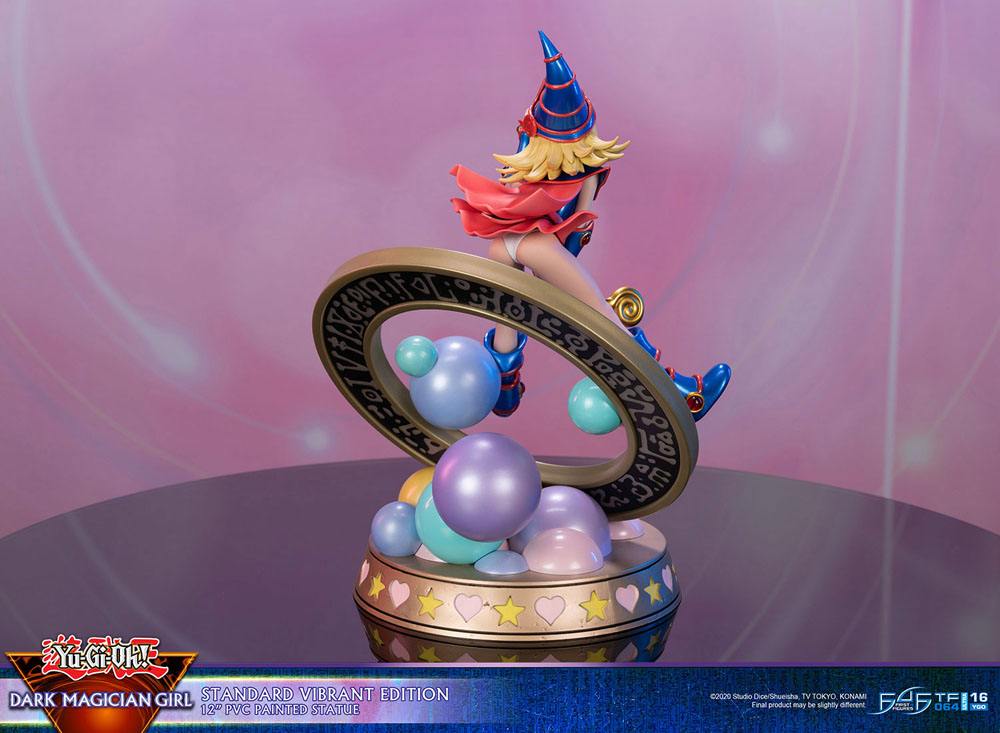 Figurine de Dark Magician Girl en PVC, posée dans un cercle magique décoré de runes, avec des sphères pastel à la base. Elle porte sa tenue bleue et rose emblématique, avec un chapeau pointu et une pose dynamique.