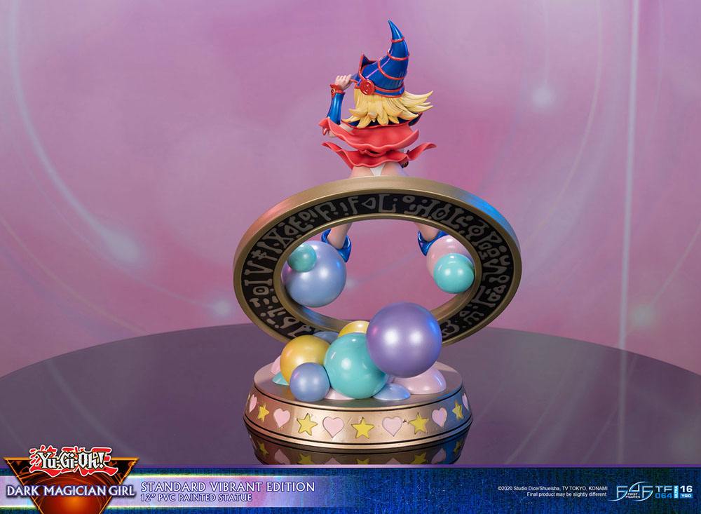 Figurine de Dark Magician Girl en PVC, posée dans un cercle magique décoré de runes, avec des sphères pastel à la base. Elle porte sa tenue bleue et rose emblématique, avec un chapeau pointu et une pose dynamique.