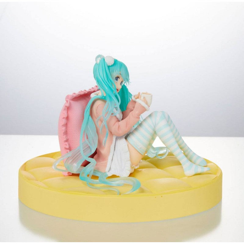 Figurine de Hatsune Miku en tenue pastel décontractée, assise avec une tasse dans les mains, ambiance cosy et kawaii.