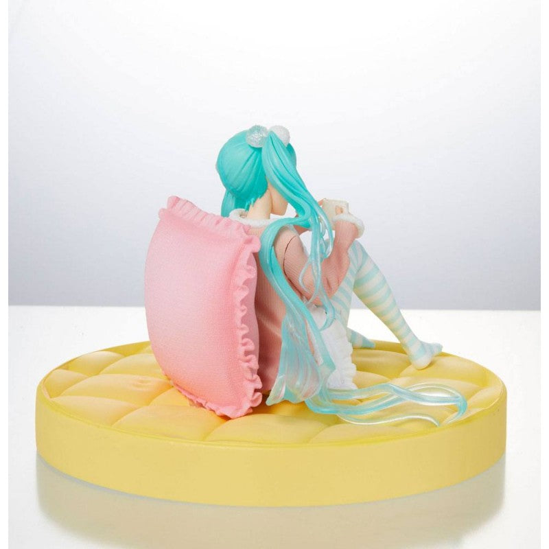 Figurine de Hatsune Miku en tenue pastel décontractée, assise avec une tasse dans les mains, ambiance cosy et kawaii.