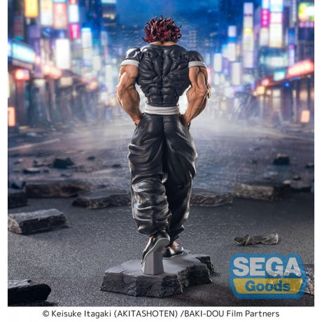 Figurine Baki Luminasta Yujiro Hanma par Sega, représentant Yujiro en tenue noire, mains dans les poches, cheveux rouges et posture menaçante sur un socle urbain.